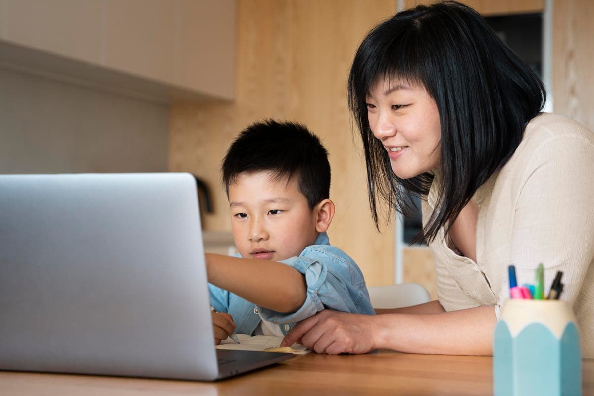 Parent helping a primary school child during an online lesson at home