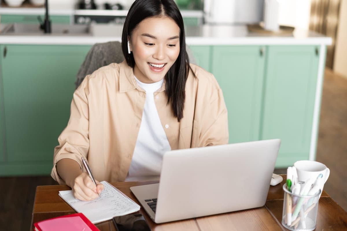 Student taking notes during an online tuition lesson at home in Singapore